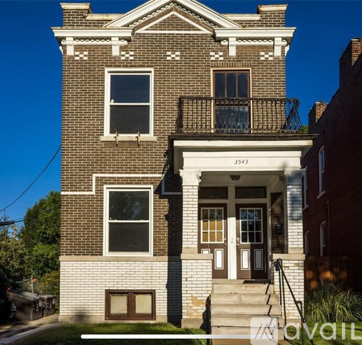 A two-story brick house with a balcony on the second floor.