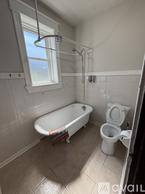 A bathroom with a tub, toilet and shower.