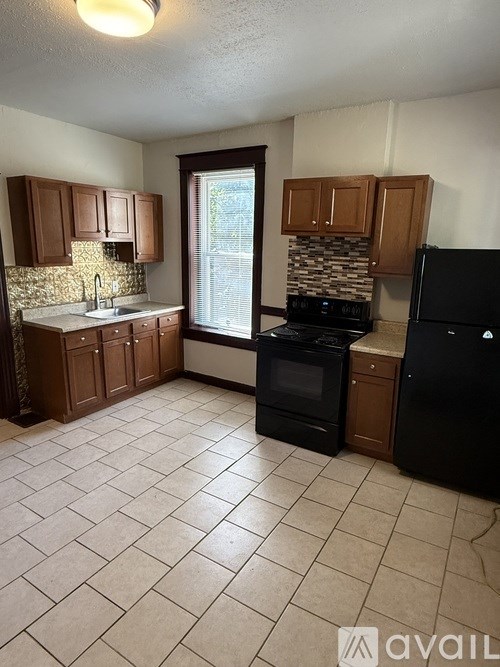 A kitchen with black appliances and brown cabinets.