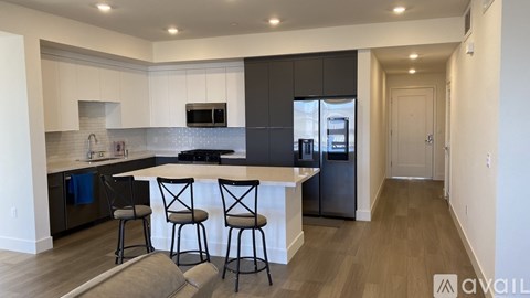 A modern kitchen with a bar area and a refrigerator.
