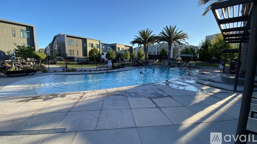 A pool area with a clear blue sky above and buildings in the background.
