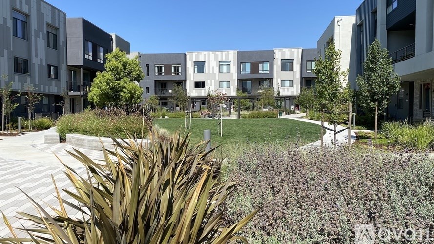 A modern apartment complex with a well-maintained garden in the foreground.