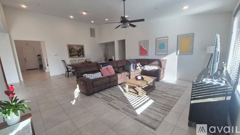 A living room with a brown couch and a ceiling fan.