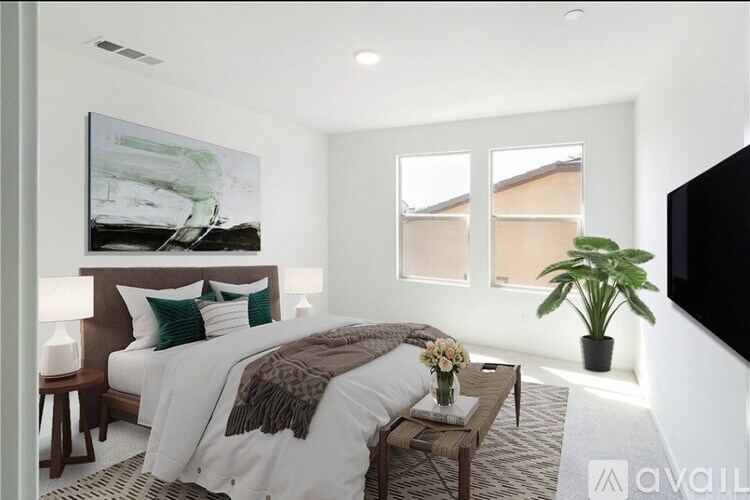 A bedroom with a large bed, a painting on the wall, and a potted plant.