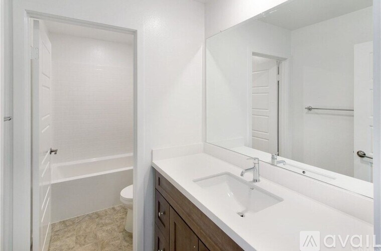 A white bathroom with a sink, mirror, and bathtub.