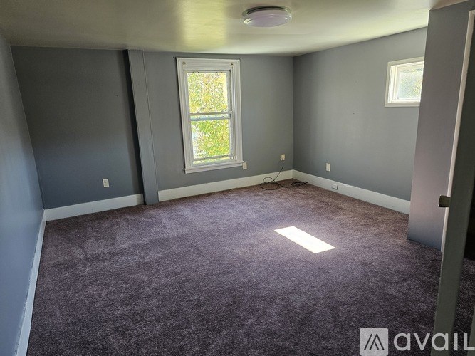 A room with a window and a carpeted floor.
