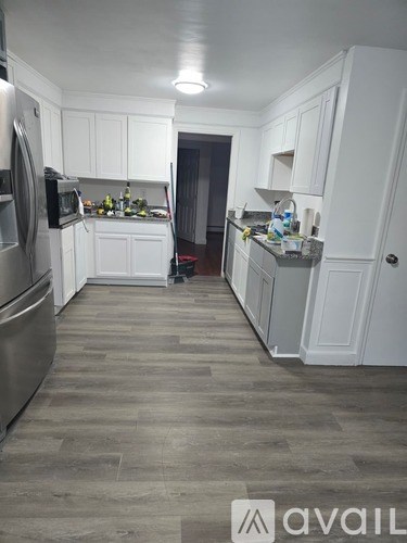 A kitchen with white cabinets and a wooden floor.