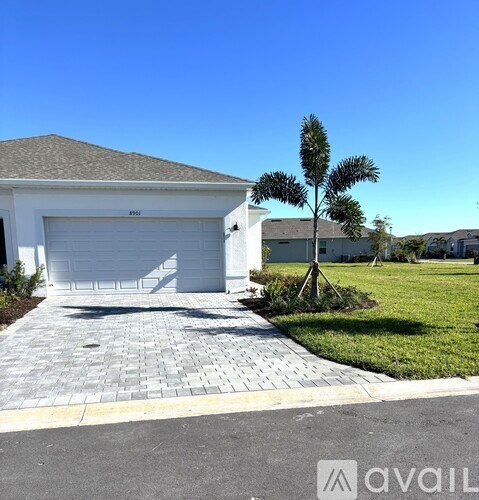 A house with a white garage door and a driveway made of interlocking paving stones.