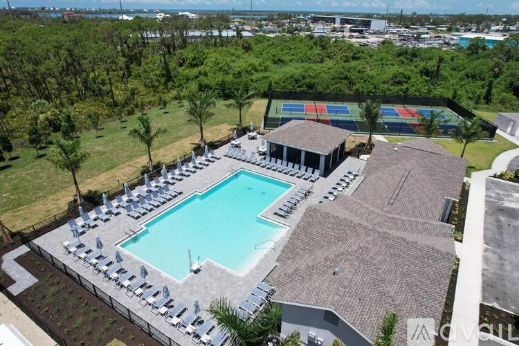 An aerial view of a pool surrounded by chairs and a building with a trampoline in the background.