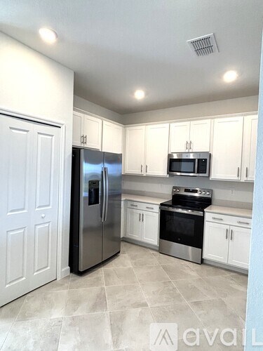 A kitchen with white cabinets and a black fridge.