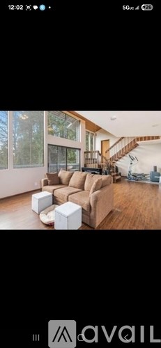 A modern living room with a large sectional sofa and a staircase in the background.