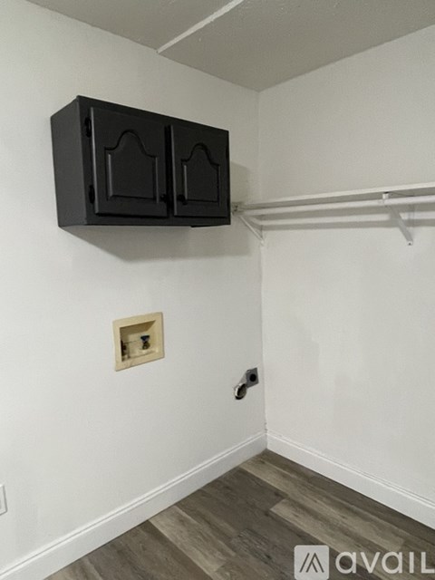 A black cabinet with three doors is mounted on a white wall.