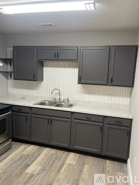 A kitchen with dark grey cabinets and a white sink.