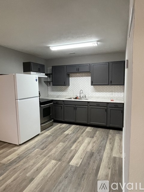 A kitchen with a white refrigerator and wooden flooring.
