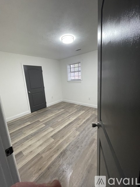 A room with a black door and a window with white blinds.