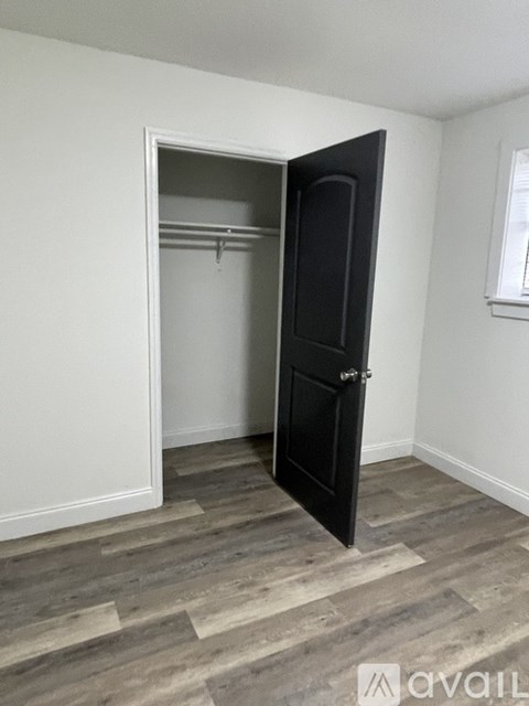 A room with a black door and wooden flooring.