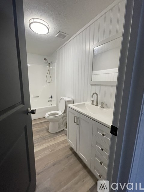 A bathroom with a toilet, sink, and mirror.