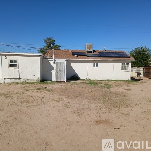 A white house with a closed door and a small window is surrounded by a dirt field.