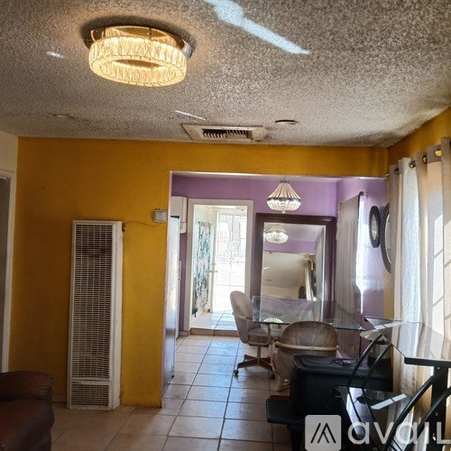 A living room with a purple wall and a ceiling fan.