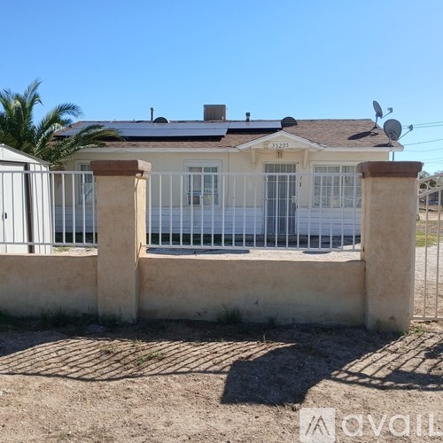 A house with a white fence and a satellite dish on the roof.