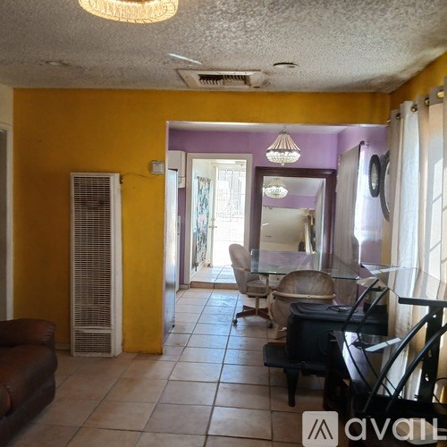 A living room with a purple wall and a brown leather couch.