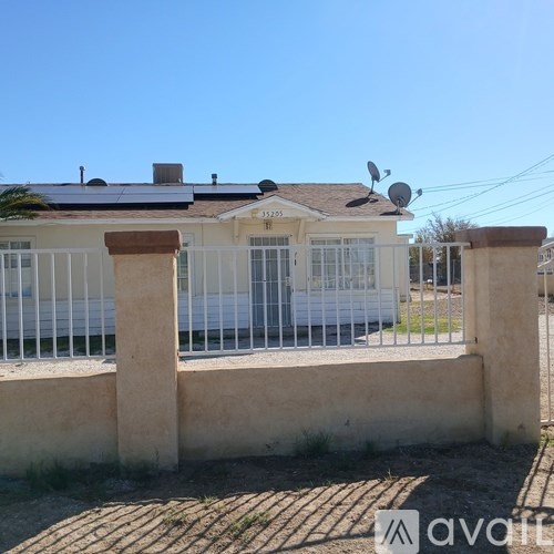 A house with a white fence and a satellite dish on the roof.