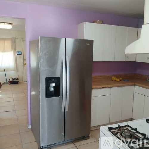 A stainless steel refrigerator in a kitchen with purple walls.
