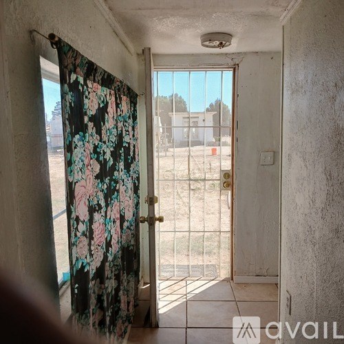 A room with a floral curtain and a view of a fenced area outside.