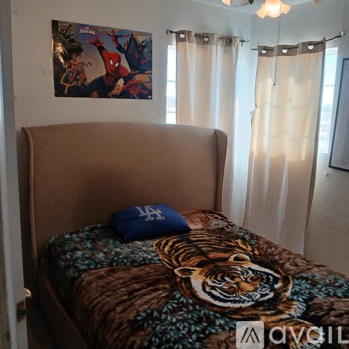 A bed with a tiger print blanket and a blue pillow with a Dodgers logo on it.