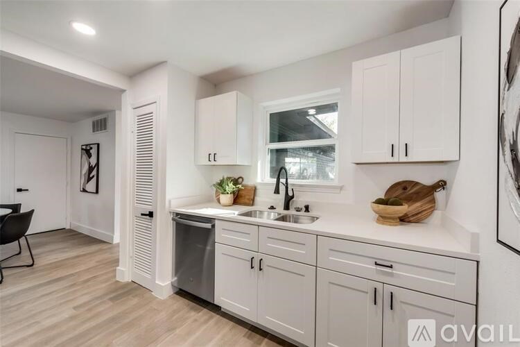 A kitchen with white cabinets and a wooden floor.