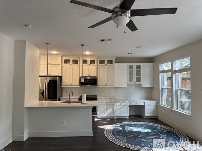 A kitchen with white cabinets and a ceiling fan.