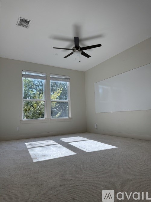 A room with a ceiling fan and two windows.