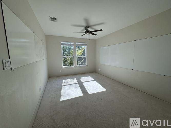 A room with a ceiling fan and a window letting in sunlight.