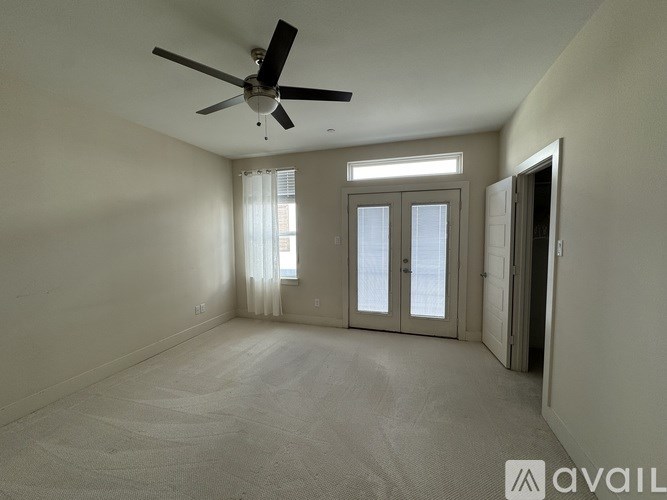 A spacious room with a ceiling fan and sliding glass doors.