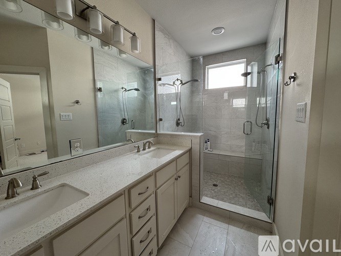 A bathroom with a sink, mirror, and shower.