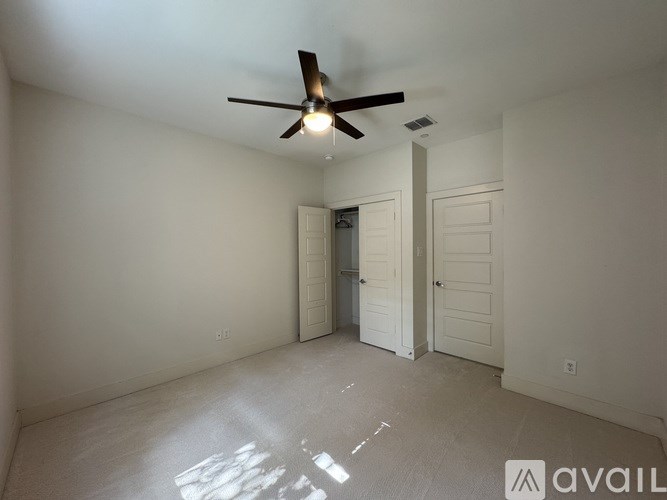 A room with a ceiling fan and two doors.