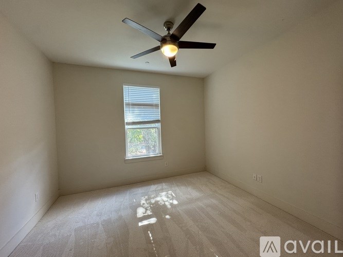 A room with a ceiling fan and a window with blinds.