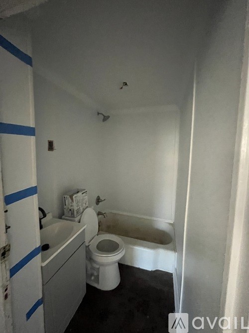 A bathroom with a toilet, sink, and a wall with blue tape on it.