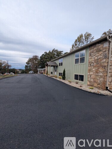 A stone building with a green wall and a black road in front.