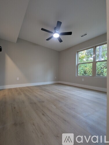 A room with a ceiling fan and wooden flooring.