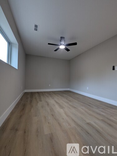 A room with a ceiling fan and wooden flooring.