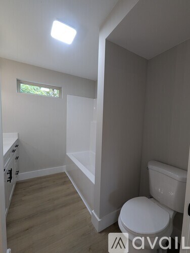 A bathroom with a toilet, sink, and window.