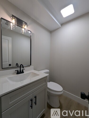 A bathroom with a sink, toilet and mirror.