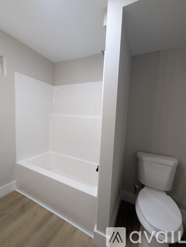 A white toilet in a small bathroom with a white bathtub.