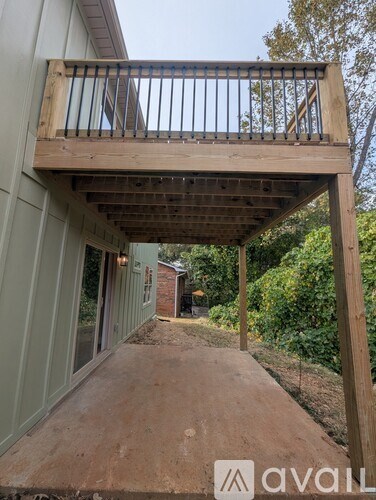 A wooden deck with a metal railing and a small building in the background.