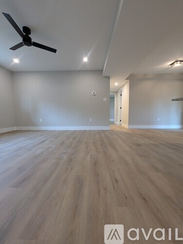 A room with a ceiling fan and wooden flooring.