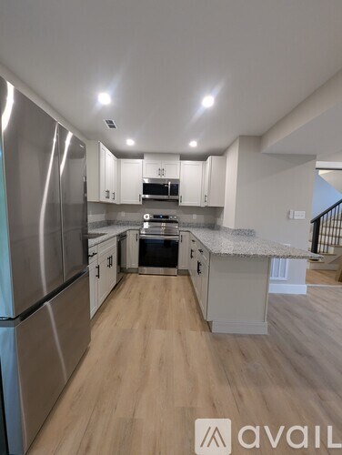 A modern kitchen with stainless steel appliances and wooden flooring.