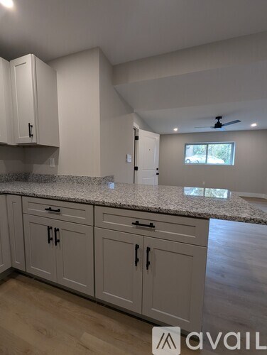 A kitchen with white cabinets and a marble countertop.