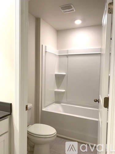 A white toilet is in a small bathroom with a walk-in shower.