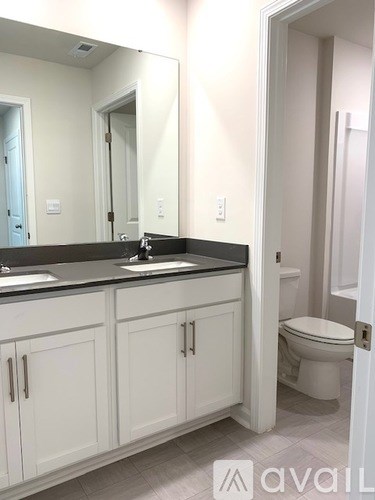 A bathroom with a sink, toilet and cabinets.